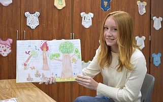 Lake Hamilton High School junior Kaitlin Guthrie holds up her book "Nature's Story" on Thursday inside a classroom. (The Sentinel-Record/Donald Cross)